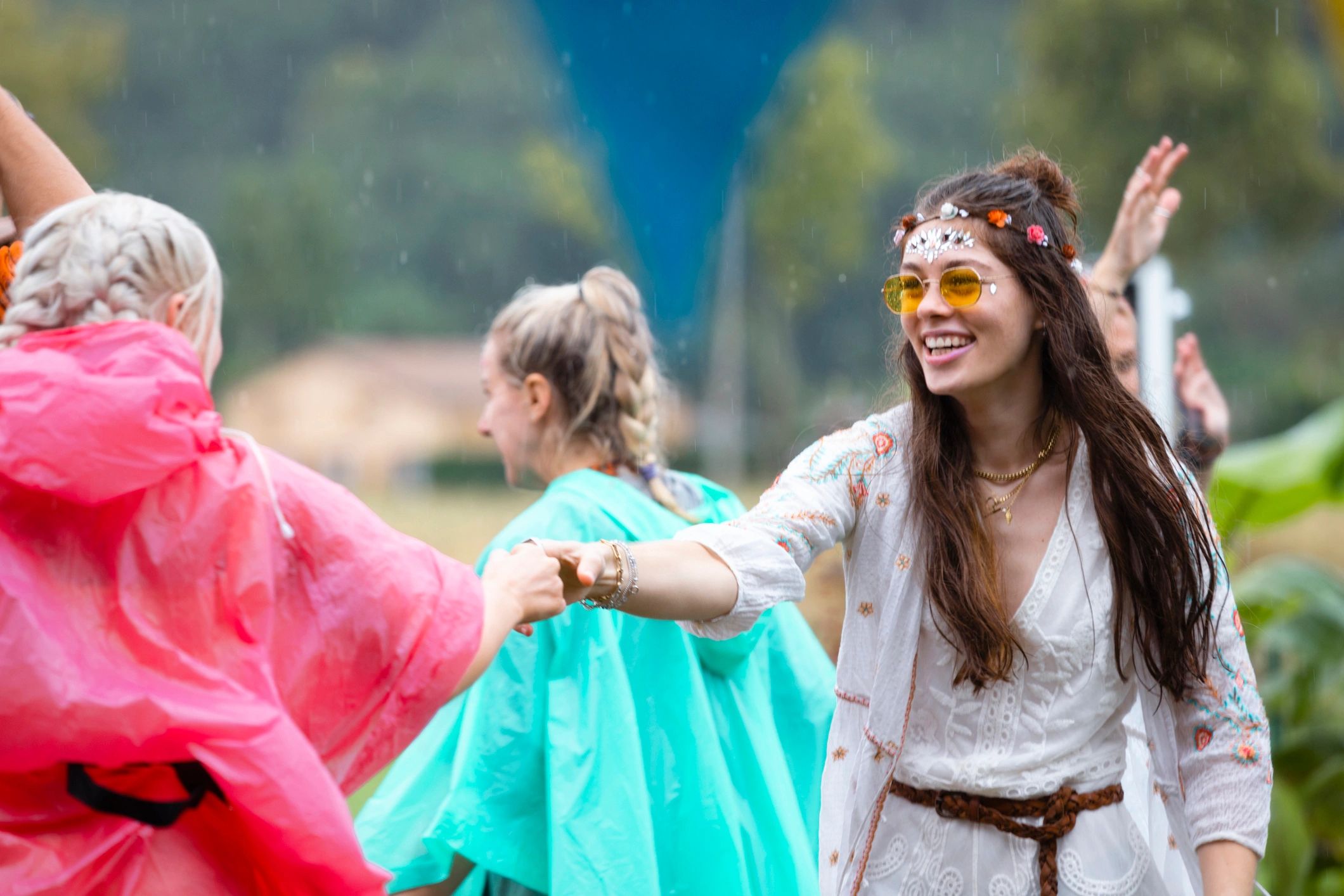 Friends dancing together at a rainy festival